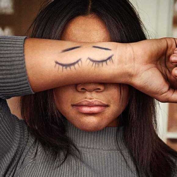 Fotografi: En flicka i tonåren håller underarmen framför ögonen. På armen har hon ritat två ögon som blundar.