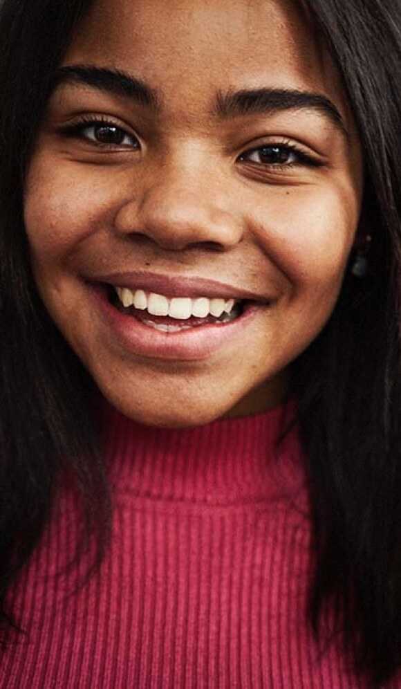 Fotografi: En tonårstjej som ler tittar in i kameran.