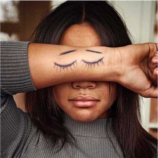 Fotografi: En flicka i tonåren håller underarmen framför ögonen. På armen har hon ritat två ögon som blundar.